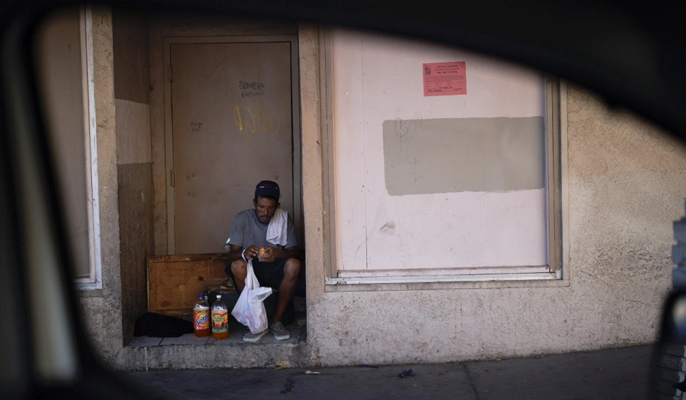 A man, who is homeless, looks at some refreshments in a bag given to him by Maribel Padilla of the Brown Bag Coalition, Thursday, July 20, 2023, in Calexico, Calif..jpg